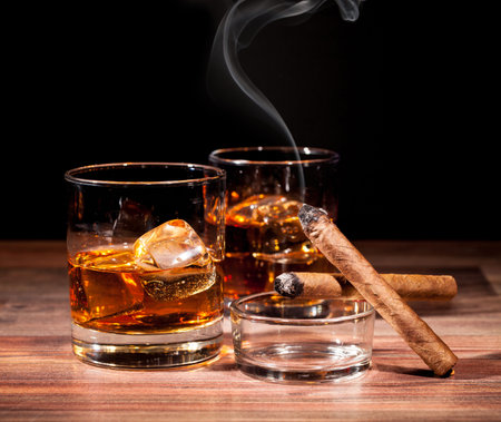 Whiskey drink with smoking cigar on wooden tableの写真素材