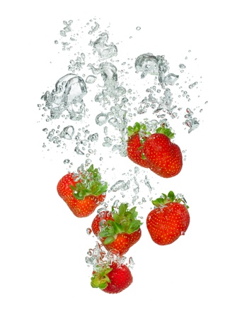 Isolated shot of strawberry falling into water, isolated on white backgroundの写真素材