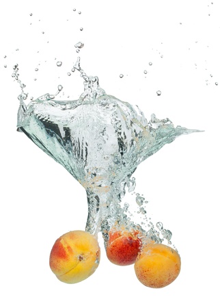 Isolated shot of apricots falling into water, isolated on white backgroundの写真素材