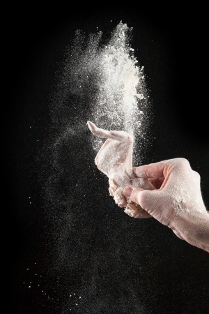 Chicken wing with flour in freeze motion, isolated on black backgroundの写真素材