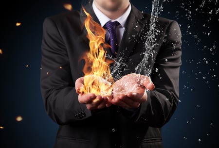 Businessman with fire and water in hands  Concept of threats and solutions as so as manager responsibility and powerの写真素材