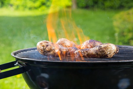 Chicken legs on barbecue grill with fireの写真素材