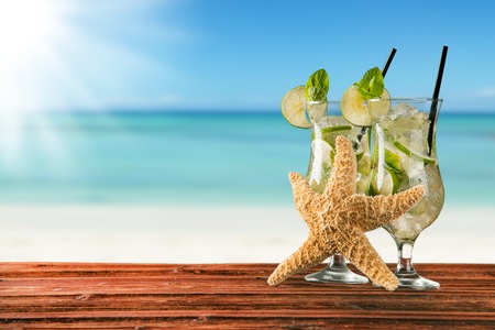 Exotic summer drinks served on wood  Blur sandy beach as backgroundの写真素材