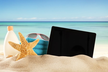 Concept with summer beach, tablet and accessories, blur sea on backgroundの写真素材