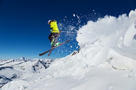Alpine skier skiing downhill, blue sky on background Alpine skier skiing downhill, blue sky on background