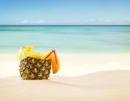 Sandy beach with fresh drink in pineapple fruitの写真素材
