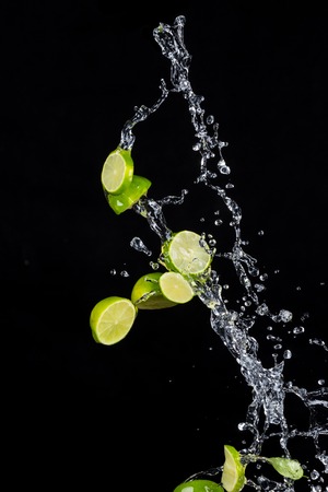 Fresh limes with water splashes isolated onblack backgroundの写真素材