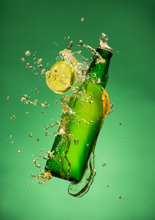 Bottle of fruit beer with splash around on green background.の写真素材