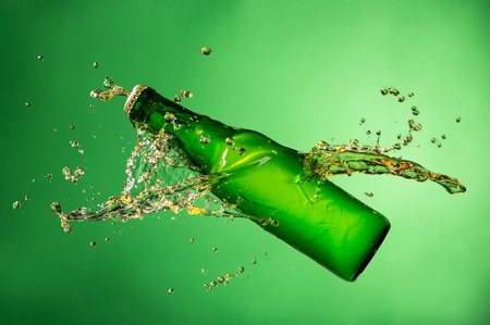 Bottle of beer with splash around on green backgroundの写真素材