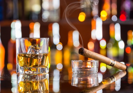 Whiskey drink with smoking cigar on bar counterの写真素材