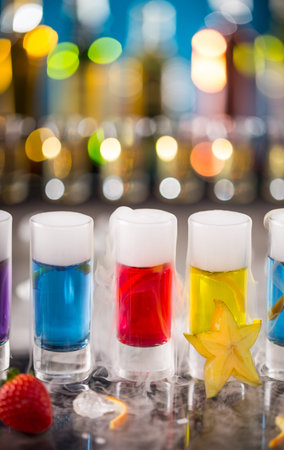 Variation of hard alcoholic shots with dry ice smoke effect, served on bar counter. Blur bottles on...