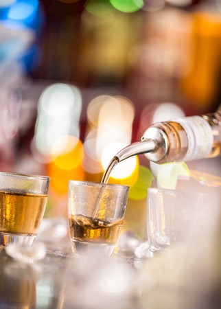 Barman pouring hard spirit into glasses in detailの写真素材