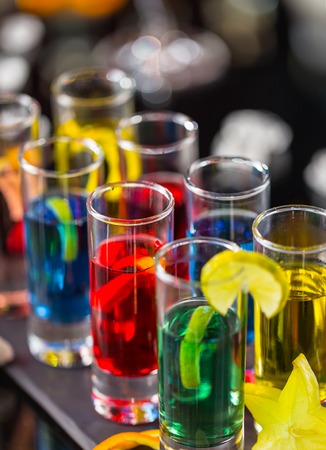 Variation of hard alcoholic shots served on bar counter. Blur bottles on backgroundの写真素材