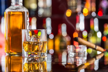 Whiskey drink on bar counter with blur bottles on backgroundの写真素材