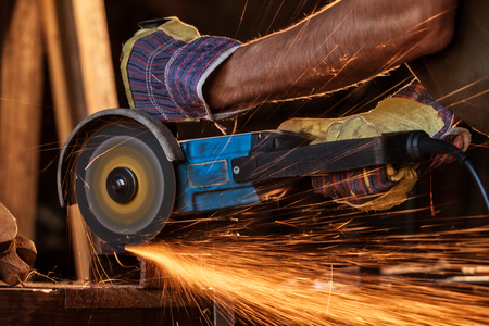 Close-up of worker cutting metal with grinder. Sparks while grinding iron. Low depth of focusの写真素材