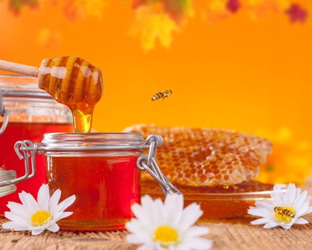 Fresh honey jar with dipper, served on wooden planksの写真素材