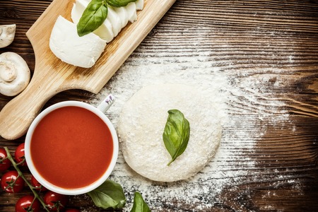 Pizza dough with ingredients on wood, shot from aboveの写真素材