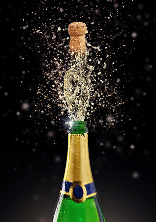 Celebration theme with splashing champagne, isolated on black backgroundの写真素材