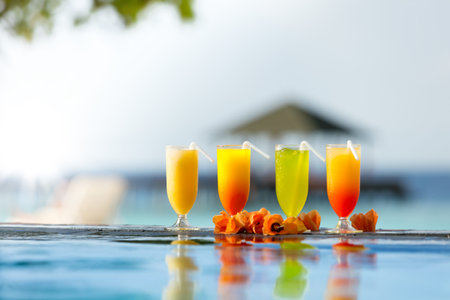 Fresh summer cocktails drinks placed next to swimming pool with ocean on background.の写真素材