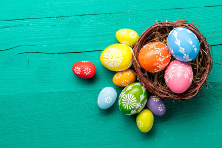 Colorful Easter eggs in basket placed on wooden planks. Copyspace for text