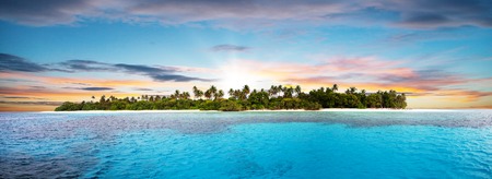Beautiful nonsettled tropical island with perfect sunset sky and azure water with coralsの写真素材