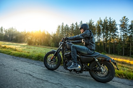 Motorcyclist riding a chopper on a road in morning sunの写真素材