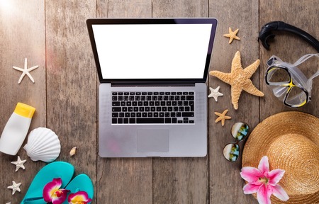 Laptop with beach accessories on wooden background. Copyspace for textの写真素材