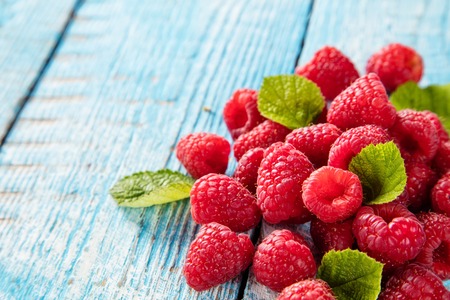 Fresh raspberry pile with leaves placed on old wooden planksの写真素材
