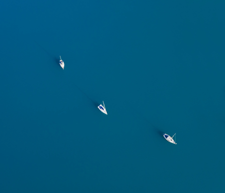Beautiful aerial view of three yachts sailling on azure waterの写真素材
