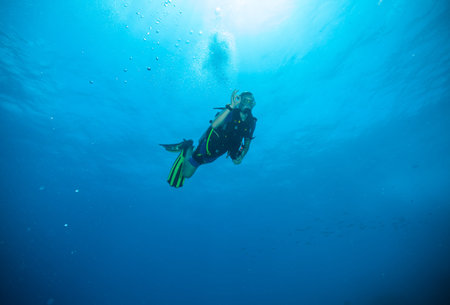 Young man scuba diver exploring sea bottom. Showing ok sign.