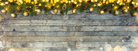 Christmas lights with fir decoration placed on old wooden planks.