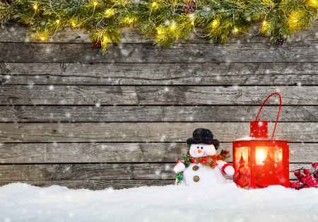 Christmas background with snowman and red lantern in snow. Fir decoration branches on topの写真素材