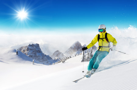 Skier on piste running downhill in beautiful Alpine landscape. Blue sky on background. Free space for textの写真素材