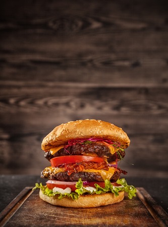 Home made hamburger with lettuce, cheese, beef meat and french fries placed on old wooden tableの写真素材
