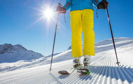 Man's legs in ski boots, standing on alpine skis in beautiful sunny day. Winter sport concept