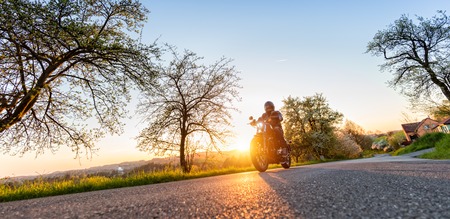 Motorcycle driver driving in beautiful sunset lightの写真素材