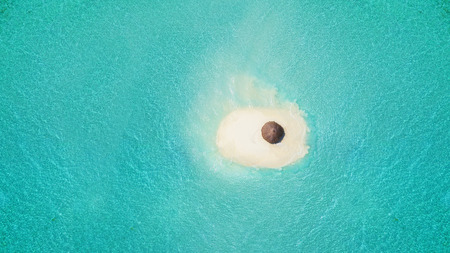 Small sandy island with umbrella, concept of relaxation and summer vacation on beach.の写真素材