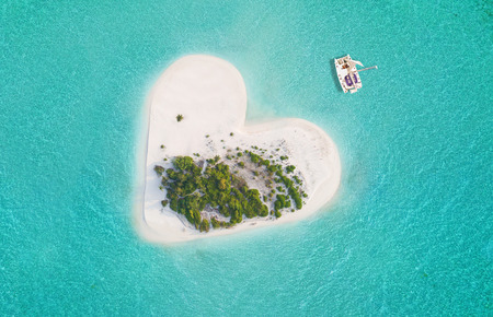 Beautiful small tropical island in heart shape, catamaran boat anchoring.の写真素材