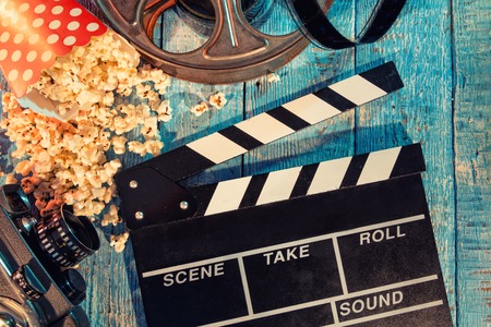 Film camera chalkboard , movie camera, roll and popcorn on wooden planks.の写真素材