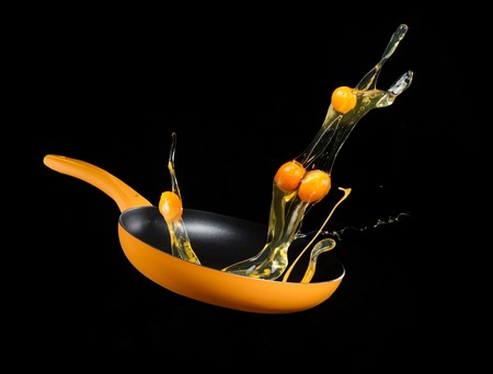 Fresh blended egs flying from a pan, isolated on black backgroundの写真素材