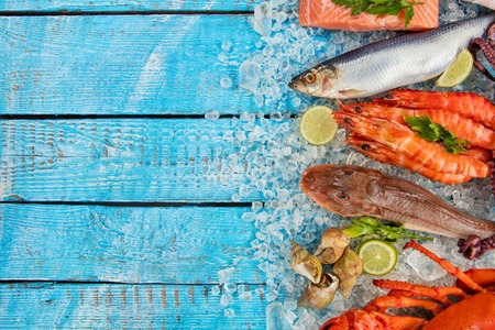 Many kind of seafood, crab, mussels, prawns, fish, salmon steak, mackerel and other shells served on crushed ice and wooden tableの写真素材