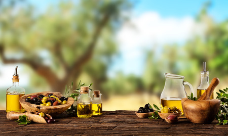 Freshly harvested olives berries in wood bowls and pressed oil in glass bottles. Still life of food preparation served on old wooden planks. Free space for textの写真素材