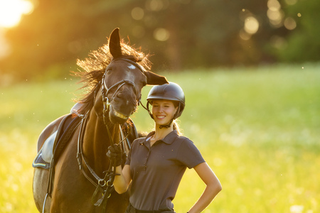Young woman rider with her horse enjoying good mood in evening sunset light. Outdoor lifestyle photographyの写真素材