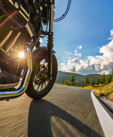 Detail of motorcycle front wheel. View from co-driver perspective, beautiful Alpine landscape in sunset light. Travel and sport photography in outdoor. Speed and freedom conceptの写真素材