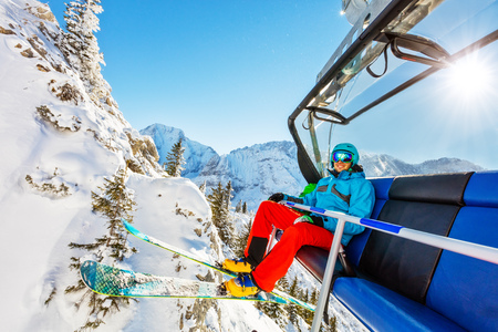Skier sitting at ski lift in high mountains during sunny day. Winter sport and recreation, leasure outdoor activities.の写真素材