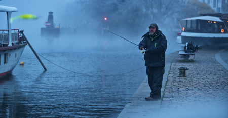 Alone fisherman, trying to catch fish in early morning. Urban fishing and outdoor pursuit activitiesの写真素材