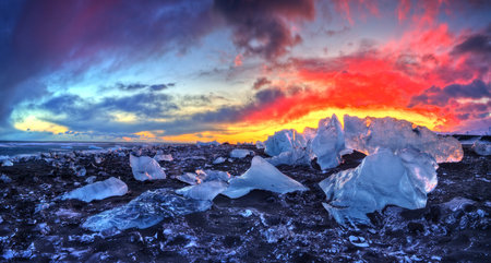 Beautiful sunset over famous Diamond beach, Iceland. This sand lava beach is full of many giant ice...
