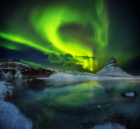 Kirkjufell mountain with beautiful aurora borealis and frozen water falls in winter, Iceland. One of the famous natural heritage in Iceland.の写真素材