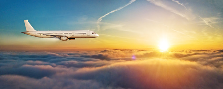 Commercial airplane jetliner flying above clouds in beautiful sunset light, side view. Concept of travel and business.の写真素材