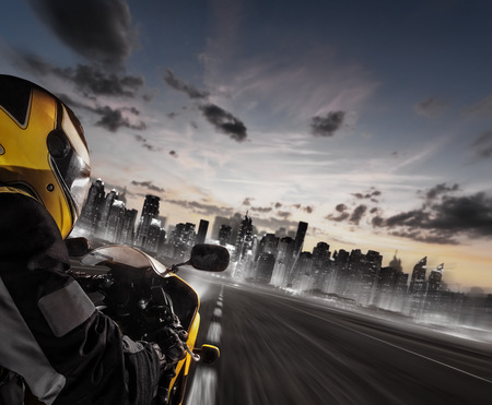Supersport motorcycle rider heading to modern city skyline. Travel, speed, freedom and transportation topic.の写真素材
